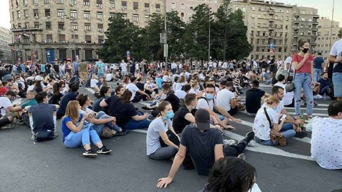 Young people wearing masks sitting on a street in Belgrade during anti-government protest on July 10, 2020. Serbia.