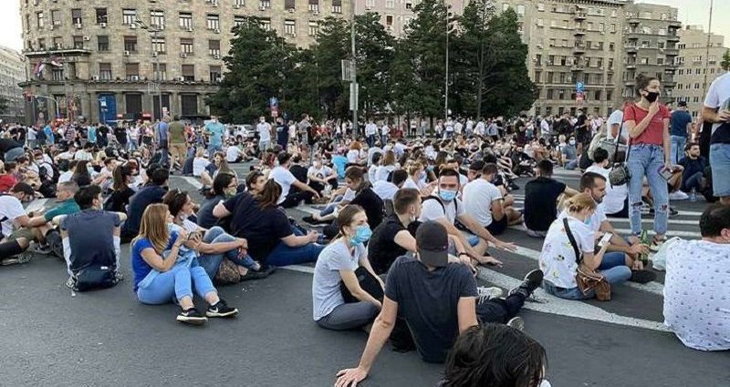 Young people wearing masks sitting on a street in Belgrade during anti-government protest on July 10, 2020. Serbia.