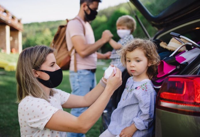 A family of four, putting on their masks while out in the countryside