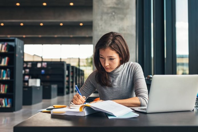 Woman taking notes from book in library