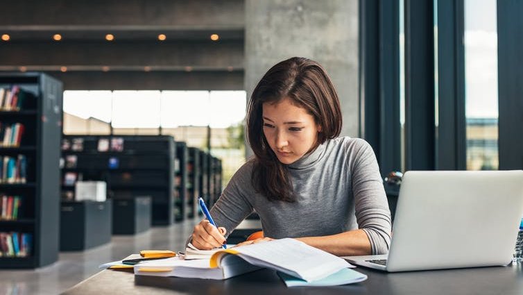 Woman taking notes from book in library