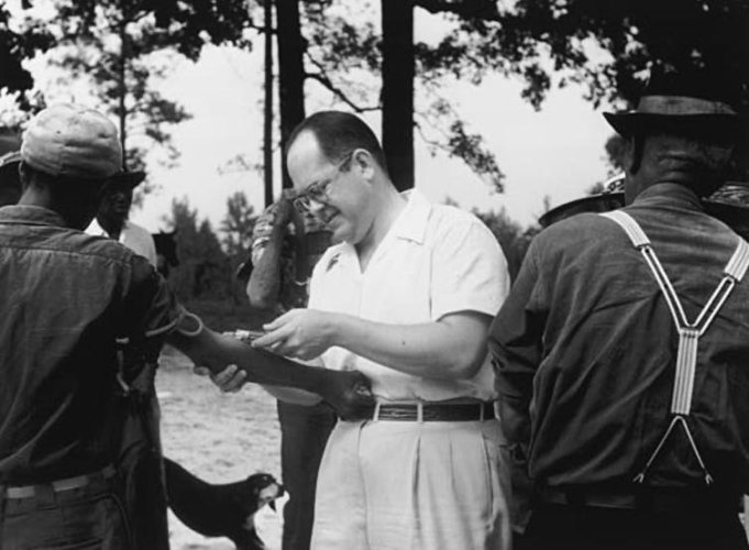 A Black participant in the Tuskegee Syphilis Study has blood drawn by a white man.