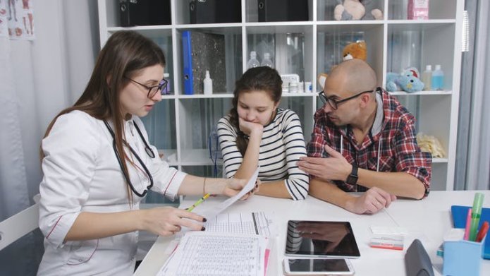 A pre-teen girl and her father consult with a female doctor.