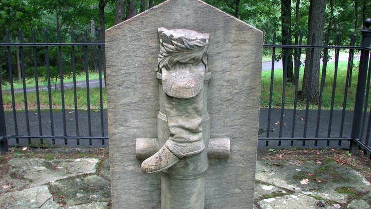 Statue of a boot hanging on a post in a park,