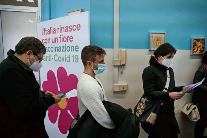 People wearing masks queuing for COVID-19 vaccination.