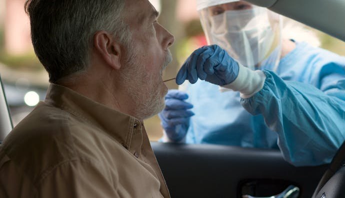 A man being a swab test while sitting in his car.