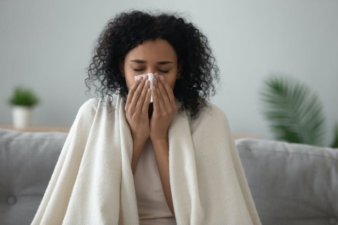 A woman with flu blowing her nose.