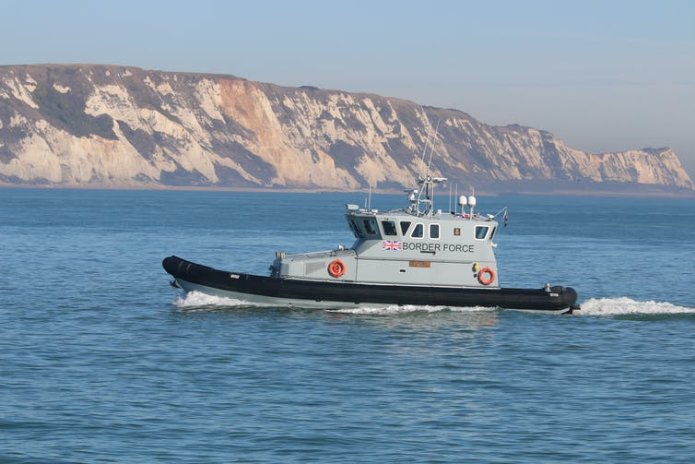 A Border Force boat pictured returning to Folkestone Harbour, with white cliffs in the background.