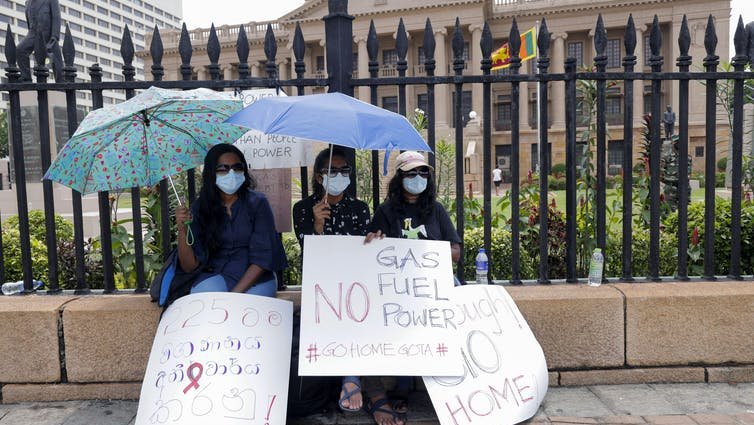 Three women with umbrellas and placards.