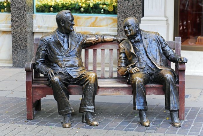 bronze sculptures of Franklin D Roosevelt and Winston Churchill on a wooden bench.