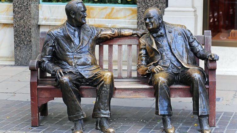 bronze sculptures of Franklin D Roosevelt and Winston Churchill on a wooden bench.