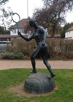 Bronze statue of tennis player Dorothy Round, in action with racquet in hand and wearing a skirt