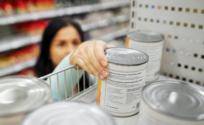 Woman reaching for tin in supermarket