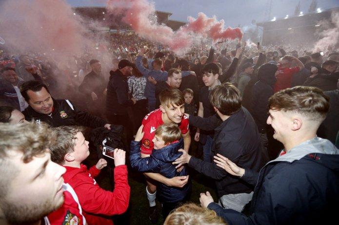 Wrexham fans celebrate on the pitch as Wrexham win the National League and promotion to League Two