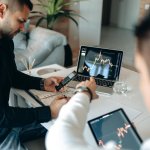 a man pointing the crypto graph on the monitor of a laptop