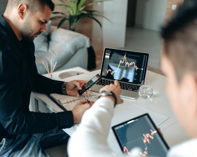 a man pointing the crypto graph on the monitor of a laptop
