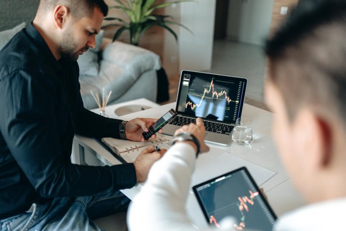a man pointing the crypto graph on the monitor of a laptop