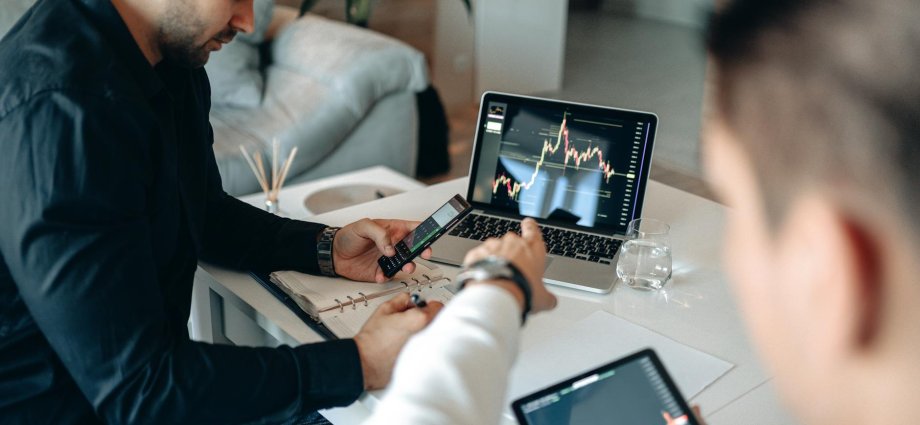 a man pointing the crypto graph on the monitor of a laptop